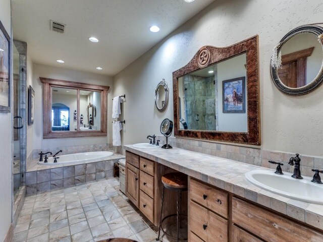 bathroom with visible vents, a shower stall, a garden tub, and a sink