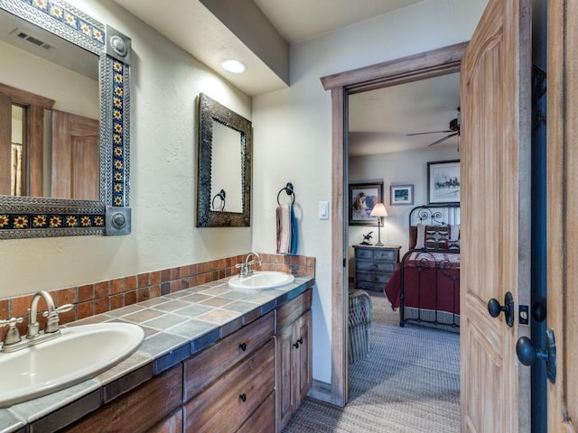 full bath featuring double vanity, ensuite bathroom, a ceiling fan, and a sink