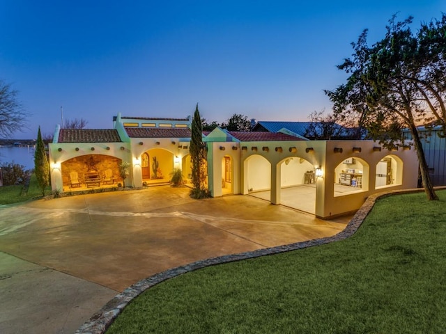 mediterranean / spanish home featuring stucco siding, concrete driveway, a tile roof, and a front yard