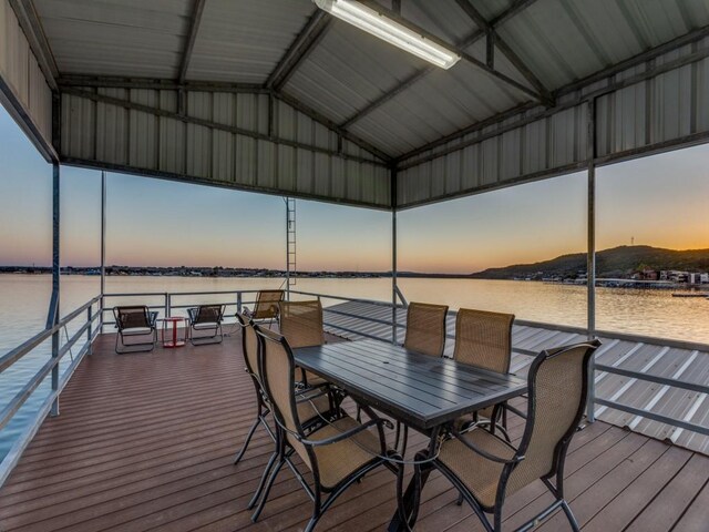 deck at dusk featuring a water view