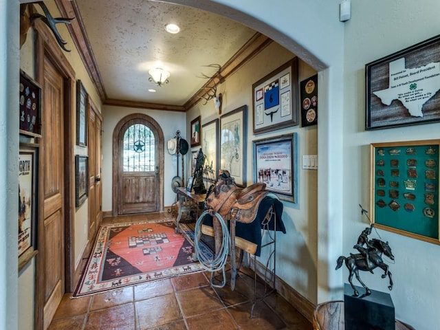 entrance foyer featuring baseboards, arched walkways, a textured ceiling, and crown molding