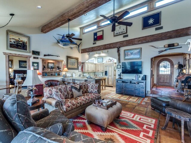 living area featuring visible vents, plenty of natural light, beam ceiling, and a ceiling fan