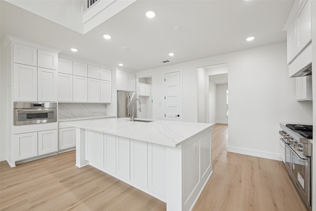 kitchen with tasteful backsplash, recessed lighting, appliances with stainless steel finishes, white cabinets, and light wood finished floors