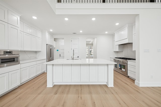 kitchen with white cabinetry, high quality appliances, light wood finished floors, and a sink