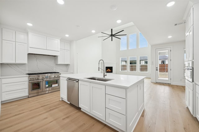 kitchen with light wood finished floors, white cabinets, appliances with stainless steel finishes, and a sink