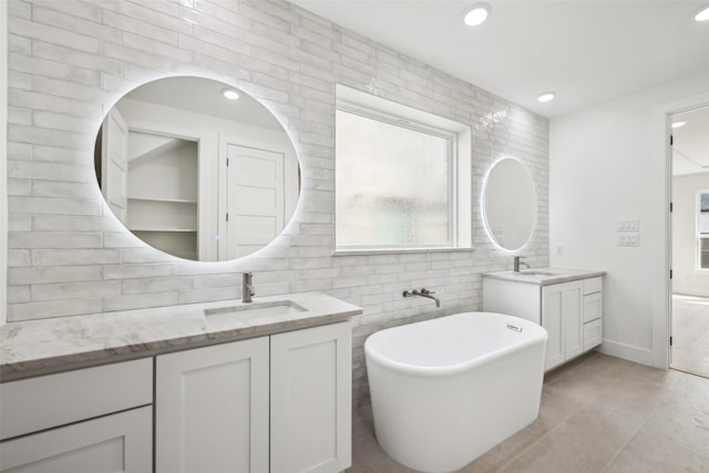 full bathroom featuring a freestanding bath, two vanities, recessed lighting, and a sink