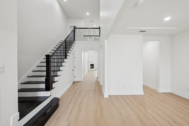 foyer with stairs, wood finished floors, visible vents, and baseboards