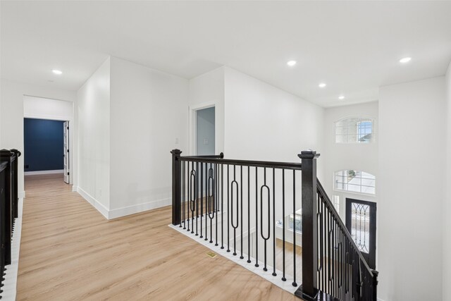 corridor featuring wood finished floors, recessed lighting, an upstairs landing, and baseboards