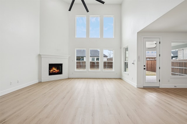 unfurnished living room featuring a fireplace, baseboards, a ceiling fan, and wood finished floors