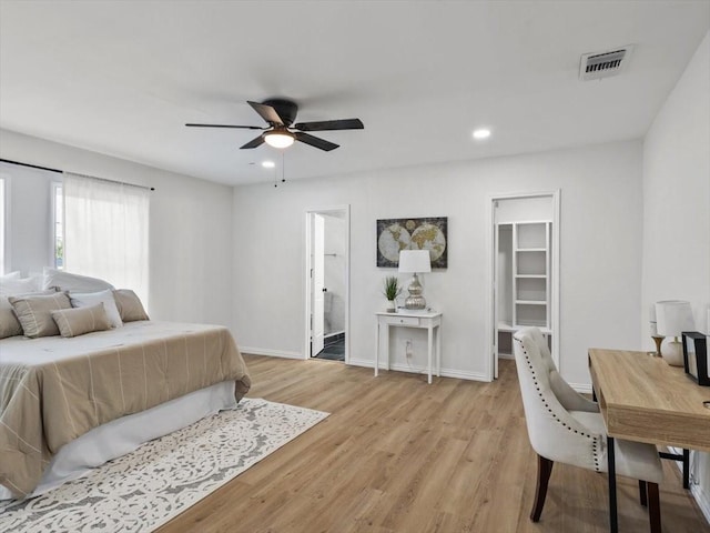 bedroom with visible vents, baseboards, light wood-style floors, and a walk in closet