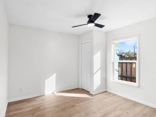 unfurnished room featuring baseboards, light wood-style flooring, and a ceiling fan