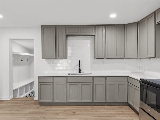 kitchen featuring range with electric cooktop, gray cabinetry, light wood-style floors, and a sink