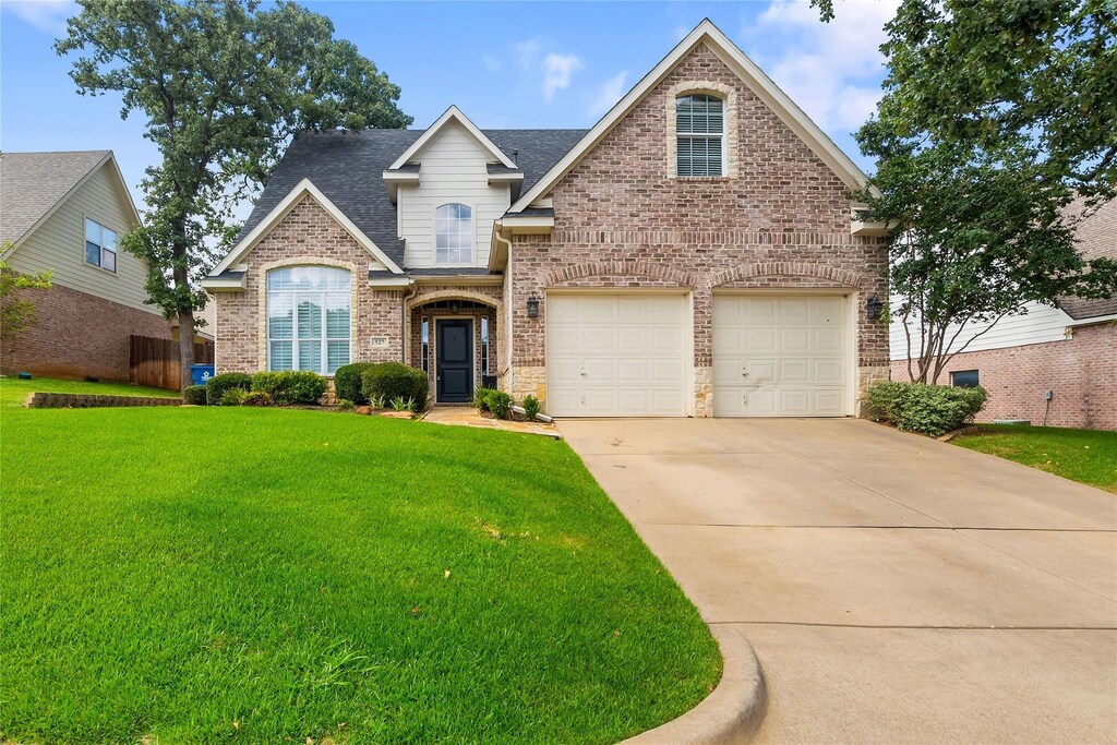 traditional home with a front yard, concrete driveway, brick siding, and a shingled roof