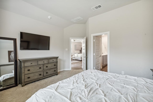 carpeted bedroom with ensuite bath, vaulted ceiling, baseboards, and visible vents