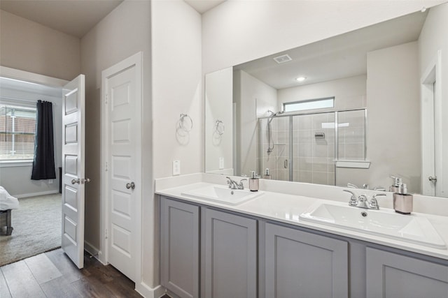 bathroom with a sink, double vanity, wood finished floors, and a shower stall