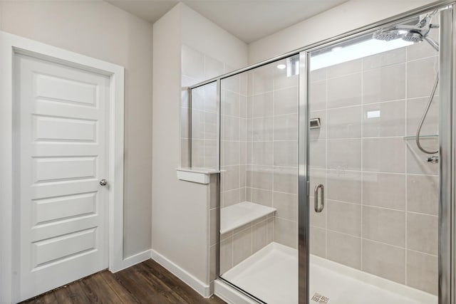 full bathroom with wood finished floors, a stall shower, and baseboards