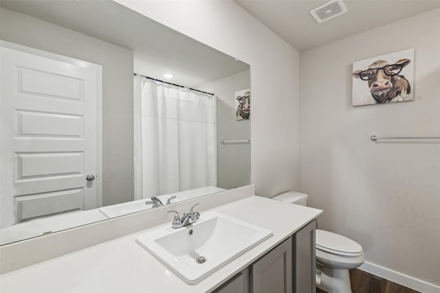 bathroom featuring visible vents, toilet, wood finished floors, baseboards, and vanity