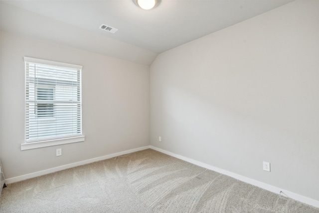 carpeted empty room featuring vaulted ceiling, visible vents, and baseboards