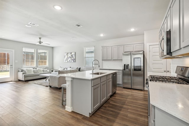 kitchen featuring visible vents, a sink, gray cabinetry, dark wood-type flooring, and appliances with stainless steel finishes