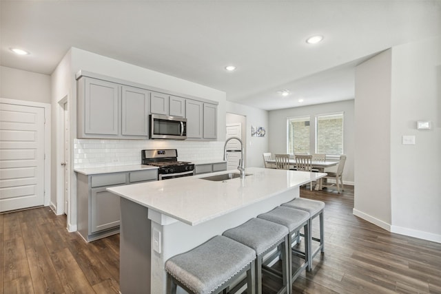 kitchen with a sink, decorative backsplash, gray cabinets, and stainless steel appliances