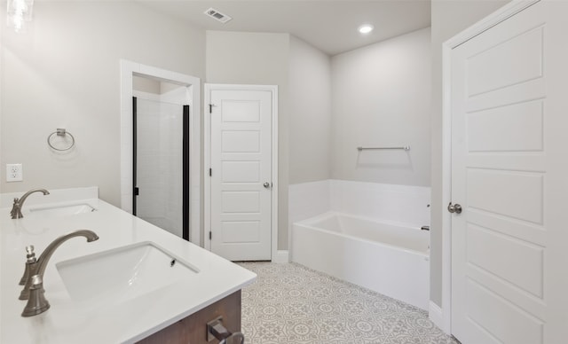 bathroom with a bath, visible vents, double vanity, and a sink