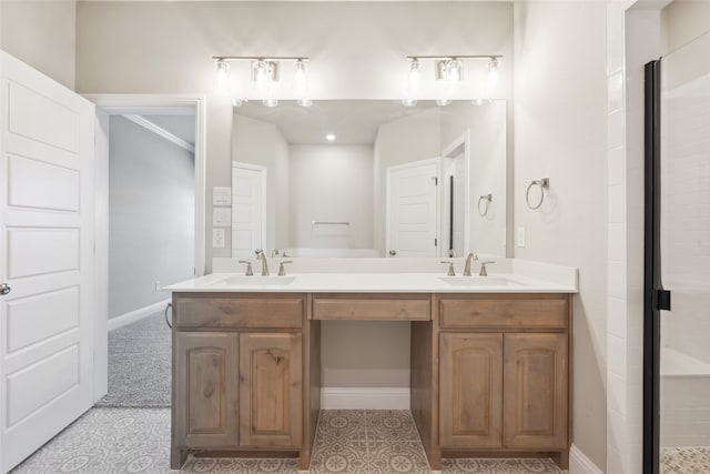 full bathroom featuring double vanity, a tile shower, baseboards, and a sink