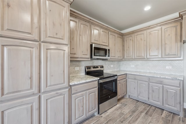 kitchen featuring light brown cabinetry, tasteful backsplash, stainless steel appliances, light wood-style floors, and light stone countertops