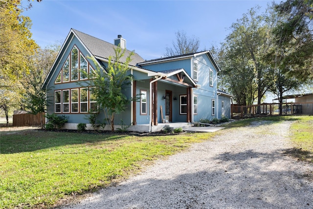 view of front of home featuring a front lawn, a porch, fence, and a chimney