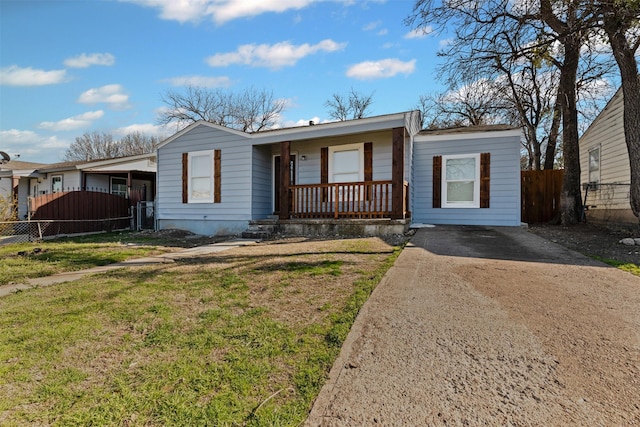 ranch-style house with a front yard, covered porch, driveway, and fence