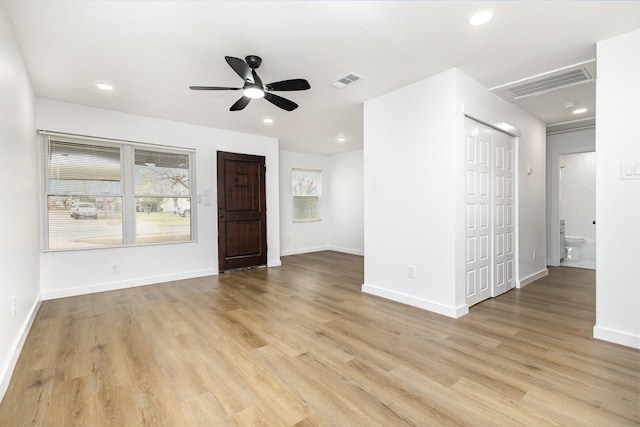 empty room with light wood-style floors, visible vents, and baseboards