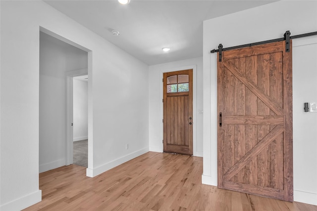 entryway featuring baseboards, light wood-style floors, and a barn door