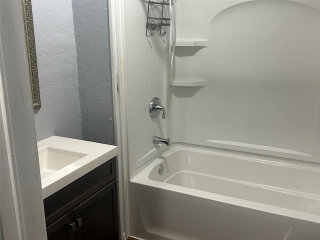 full bath featuring shower / washtub combination, vanity, and a textured wall