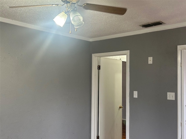 interior space featuring visible vents, a textured ceiling, ornamental molding, and a ceiling fan