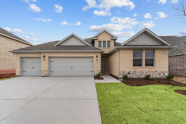 view of front facade featuring driveway, roof with shingles, a front yard, a garage, and brick siding