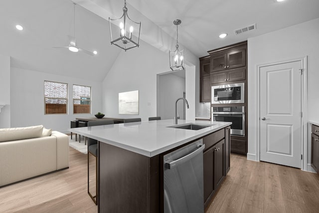 kitchen with visible vents, a sink, open floor plan, built in microwave, and dishwasher