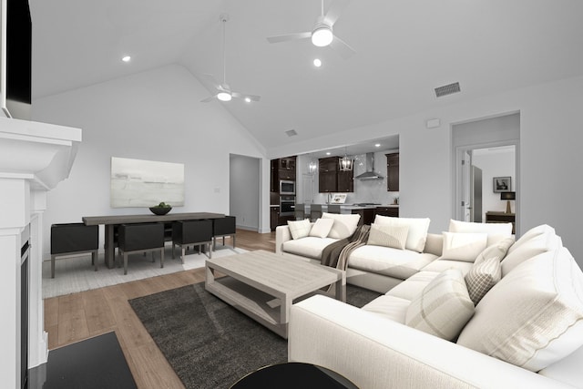 living area featuring visible vents, recessed lighting, a fireplace, light wood-style floors, and high vaulted ceiling