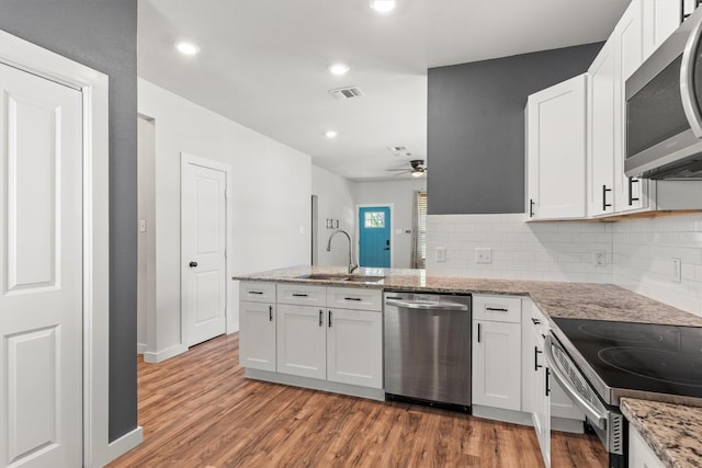 kitchen with a peninsula, white cabinetry, visible vents, a sink, and stainless steel appliances