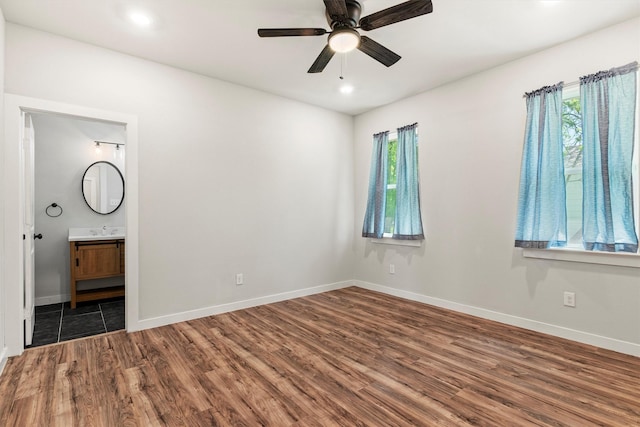 interior space featuring wood finished floors, ensuite bathroom, baseboards, and recessed lighting