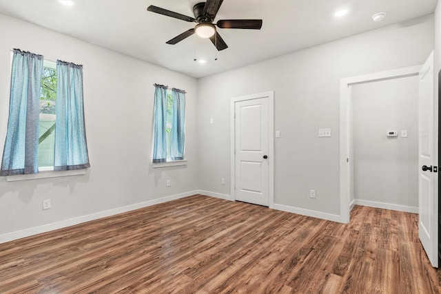 unfurnished room featuring a wealth of natural light, a ceiling fan, wood finished floors, and baseboards