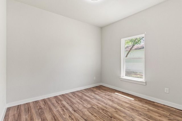 spare room with baseboards and wood finished floors