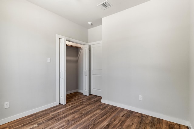unfurnished bedroom with dark wood-type flooring, visible vents, baseboards, and a closet