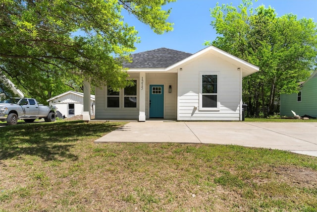 bungalow-style home featuring roof with shingles and a front lawn
