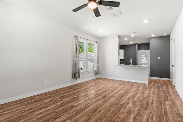 unfurnished living room with recessed lighting, a ceiling fan, visible vents, a sink, and wood finished floors