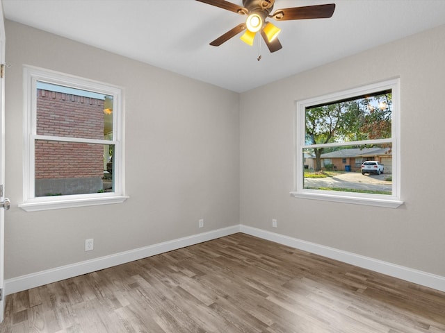 empty room featuring wood finished floors, baseboards, and ceiling fan