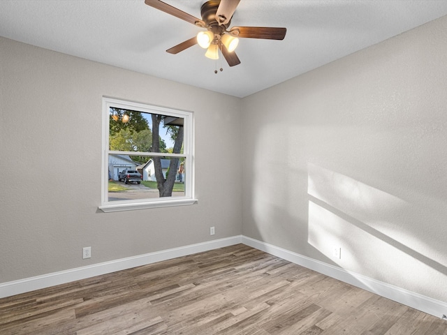 empty room with ceiling fan, baseboards, and wood finished floors