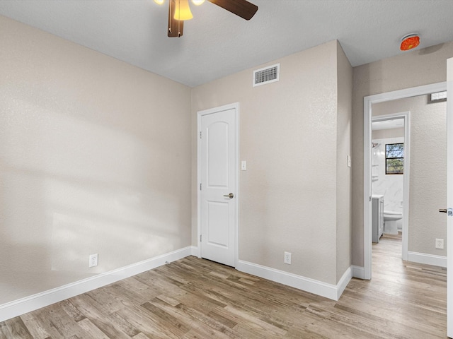 empty room featuring visible vents, light wood-style flooring, baseboards, and ceiling fan