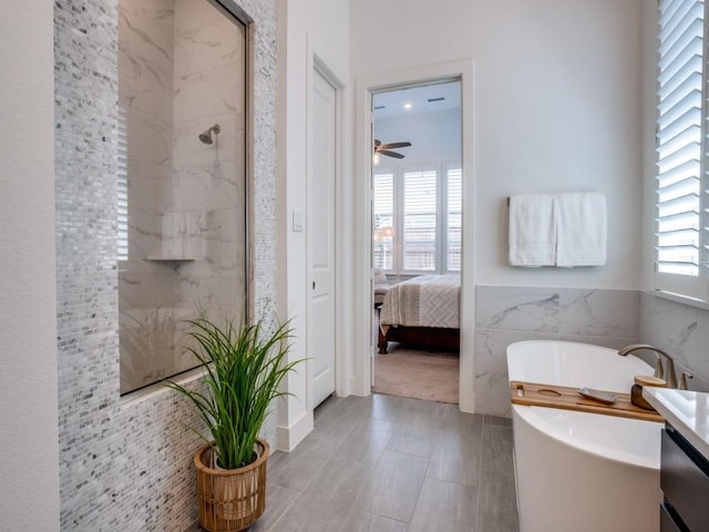 full bath featuring a freestanding tub, a marble finish shower, tile walls, and vanity