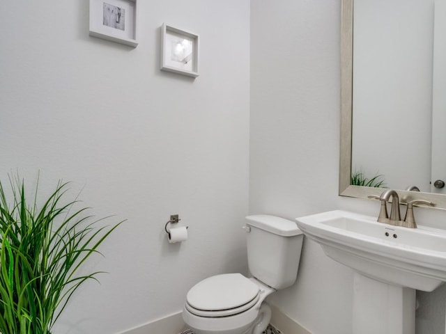 bathroom featuring a sink, baseboards, and toilet