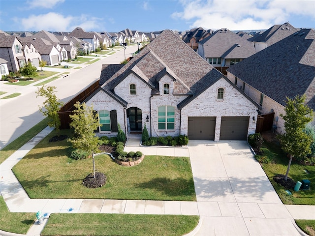 french provincial home with brick siding, a residential view, concrete driveway, and a front lawn