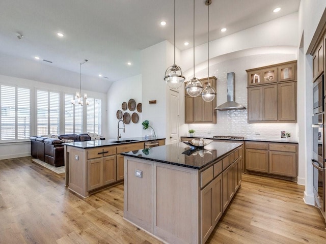 kitchen with a sink, tasteful backsplash, a kitchen island, light wood-style floors, and wall chimney range hood